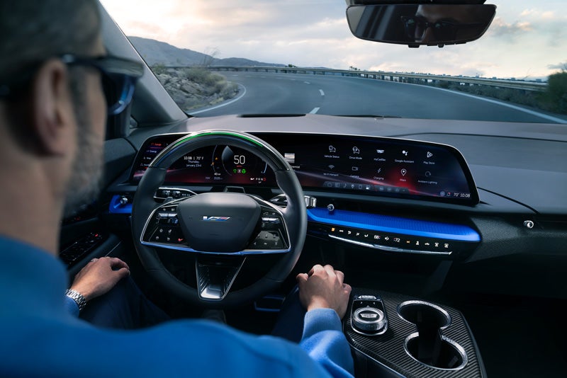 Front View of the 2026 OPTIQ-V Driving Through the Dusk Utilizing its Headlights | Cadillac of Knoxville in KNOXVILLE TN