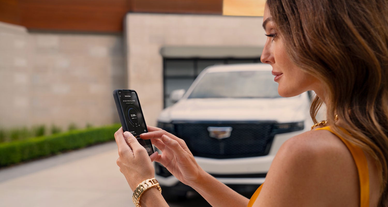 lady checking her mobile with a Cadillac vehicle background | Cadillac of Knoxville in KNOXVILLE TN